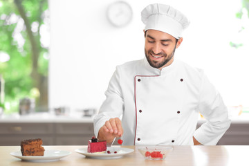 Young male chef decorating cake in kitchen