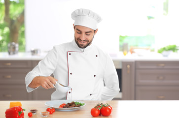 Young male chef pouring sauce on meat dish in kitchen