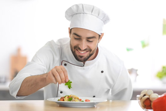Young male chef garnishing his dish in kitchen