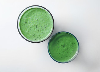 Glasses of fresh green smoothie on white background