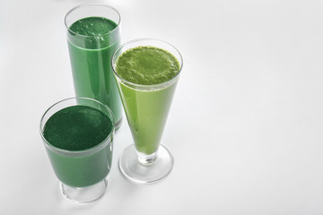 Glasses of fresh green smoothie on white background