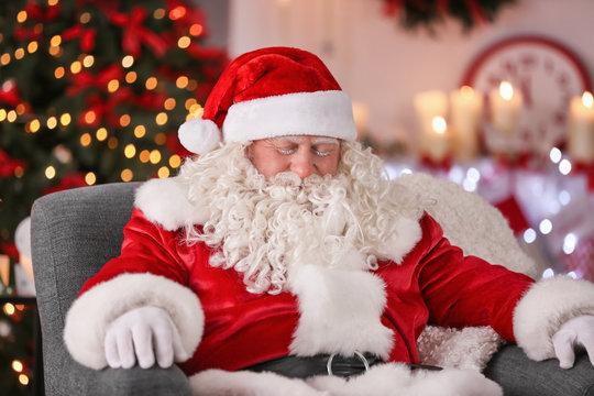 Authentic Santa Claus sleeping in armchair at room decorated for Christmas