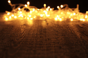 Christmas lights glowing on wooden table against black background