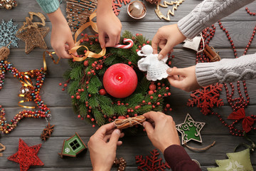 Family decorating Christmas wreath  on wooden background