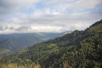Naklejka premium Горный пейзаж. Красивый вид на живописное ущелье, панорама горной местности, белые облака на синем небе. Природа и горы Северного Кавказа