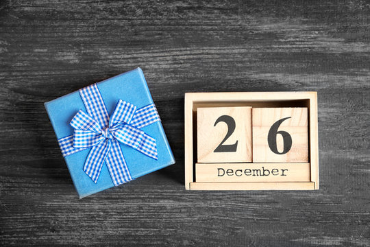 Calendar with date and gift box on wooden background. Christmas concept