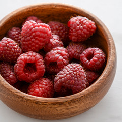 Raspberries in a wooden plate.
