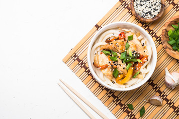 Udon stir-fry noodles with chicken on white.