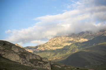 Fototapeta premium Горный пейзаж. Красивый вид на живописное ущелье, панорама горной местности, белые облака на синем небе. Природа и горы Северного Кавказа