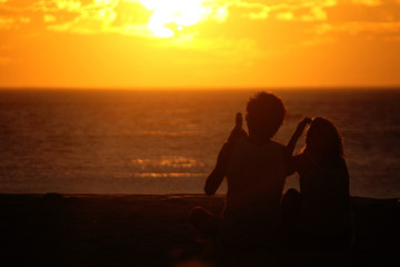 Fototapeta na wymiar Romantic couple on the beach in Brazil at colorful sunset on background