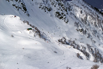 Skiers and snowboarders riding on a ski slope in Sochi mountain resort snowy winter