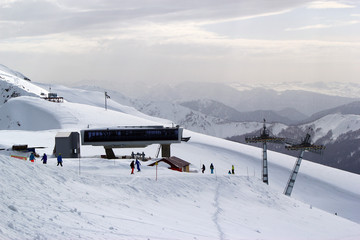 Skiers and snowboarders riding on a ski slope in Sochi mountain resort snowy winter