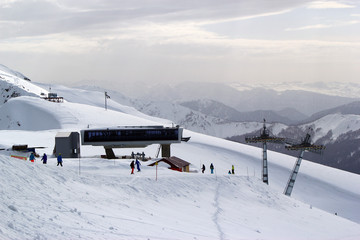 Fototapeta premium Skiers and snowboarders riding on a ski slope in Sochi mountain resort snowy winter