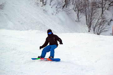 Fototapeta na wymiar Skiers and snowboarders riding on a ski slope in Sochi mountain resort snowy winter