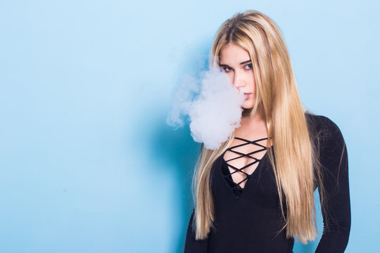Close-up Portrait of sexy young hipster smoking (vaping) girl. Vapor concept. Vaping e-Cigarette.
