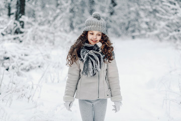Fototapeta na wymiar Little girl in winter forest in fur hat with pompon.