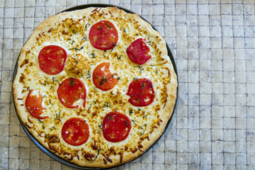 Fresh whole margarita pizza on tile