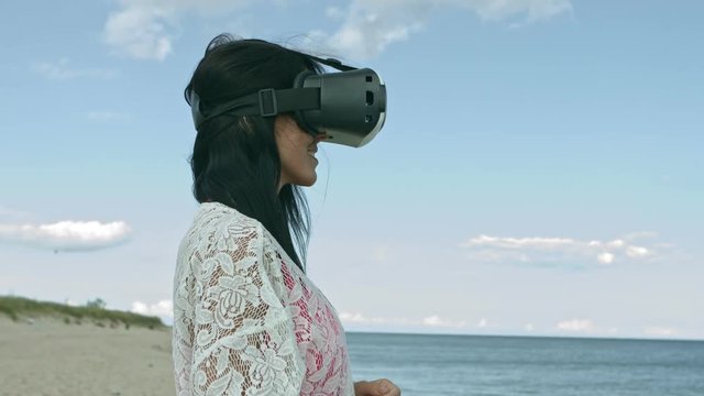 Young woman entertaining with VR-headset during sunbathing on the beach.