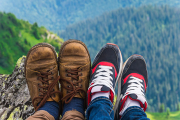 Landscape, travel, tourism. A pair of feet in the shoes against the background of the mountains. Horizontal frame