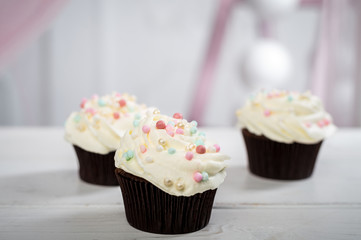 Delicious little cakes with white icing and colorful candy. Horizontal frame