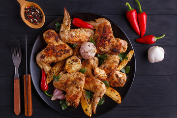 Grilled chicken wings on black  plate decorated with garlic and spices. Cooking concept, meat dishes, homemade food