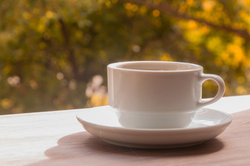 A cup of coffee on a wooden table Against the background of autumn nature