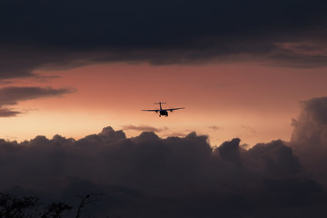 Fototapeta na wymiar airplane flying through sunset clouds