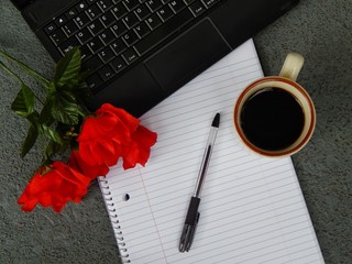 A Laptop, Notebook, Pen, Roses And A Cup Of Coffee 