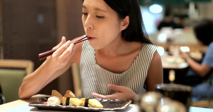 Woman enjoy sushi in Japanese restaurant