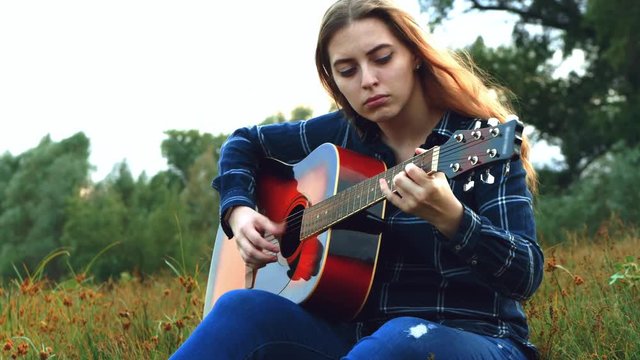 Hipster young beautiful girl, embraced by a creative start in a forest glade at noon, inspired by a forest landscape with a view of the river and simply amazing nature, picks up a new melody for a new