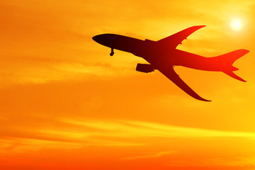 Silhouette of airplane taking off flight with orange sky background