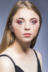 Fototapeta premium Portrait of Young Beautiful Caucasian Girl With Vivid Eyes Makeup. Posing Against Gray