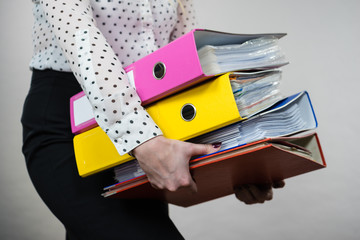 Woman holding heavy colorful binders with documents