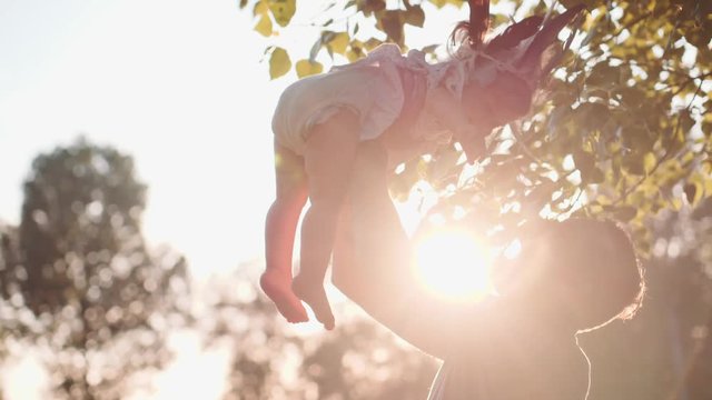 Young Father with Baby Girl Enjoying Sunny evening in the Park. Slow Motion 120 fps, 4K. Daddy playing with Toddler Daughter Near Lake Outdoors. Happy childhood and Parenthood. Cinematic Family