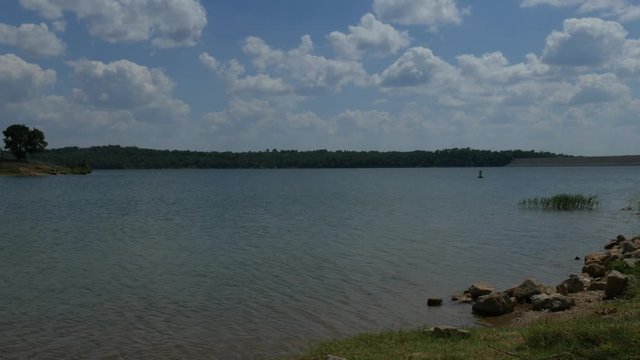 Wide shot of a lake, with a reservoir in the distance