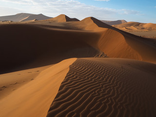 Fototapeta na wymiar Beautiful natural curved ridge line and wind blow pattern of rusty red sand dune with shade and shadow on vast desert landscape horizon, Sossus, Namib desert