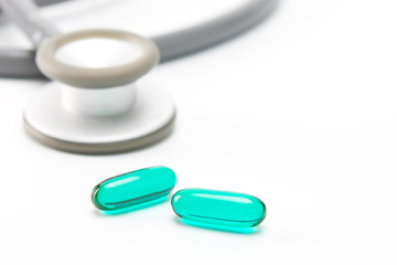 soft gel capsules of medicine and stethoscope on white background. selective focus