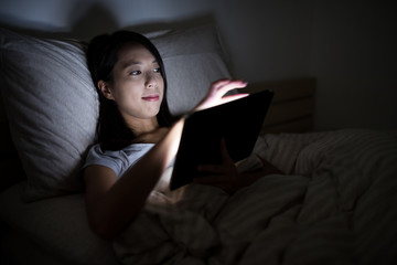 Woman using tablet computer at night