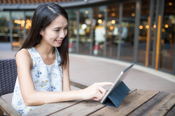 Woman using tablet computer at outdoor coffee shop
