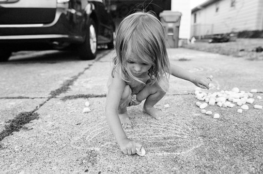 little girl chalking in driveway
