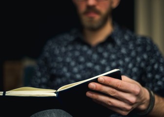 Man is sitting and reading a book at home. 