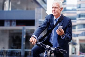 Fototapeta premium Successful businessman on bicycle with mobile phone