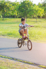 A boy riding a bike in a park on a fun vacation.