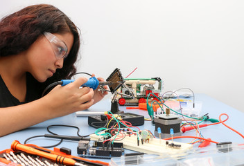 Female tech student learning how to wire a prototype circuit board