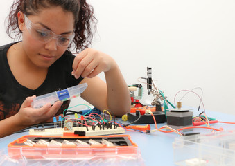 Female tech student learning how to wire a prototype circuit board