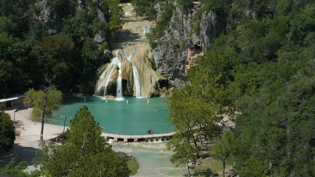 Steady wide aerial footage of Turner Falls on a bright sunny day  The 77-foot Turner Falls is one of the most popular summer destinations in Davis, Oklahoma
