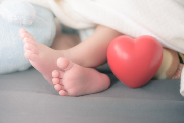baby's feet with a red heart