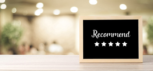 Recommend and five star on blackboard standing over blur restaurant background, copy space for text, food and drinks background, banner