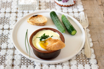 Baked egg with bread and cucumber. Rustic style, selective focus.
