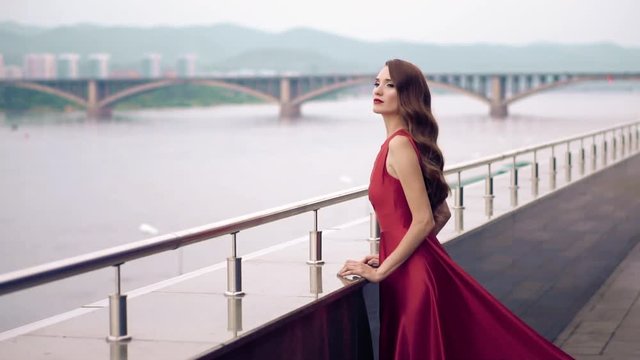 Beautiful woman in red dress outdoor. City background.